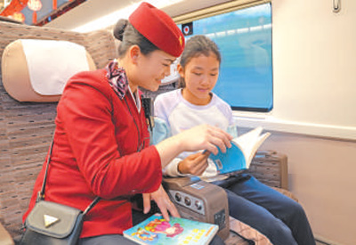 从北京开往南昌的列车上，乘务人员与小旅客一起阅读。王梦婧子摄